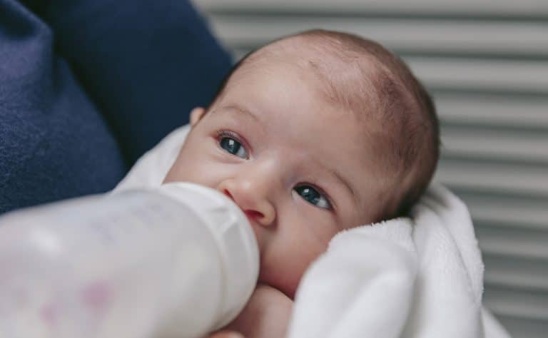 bebe au biberon dans les bras de sa mère